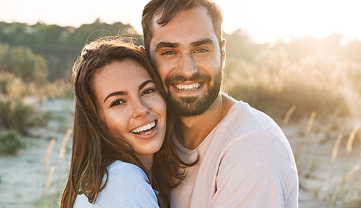 Beautiful young smiling couple spending time at the beach, hugging