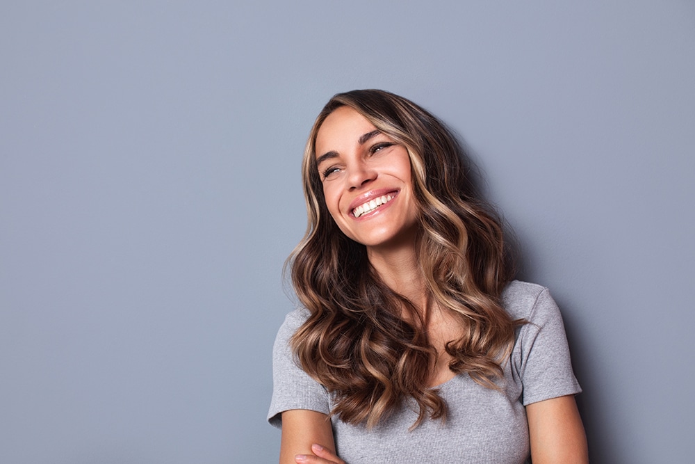 Beautiful smiling woman studio shot on gray background. Female portrait.